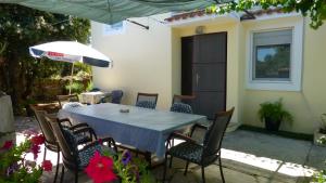 a table with chairs and an umbrella in front of a house at Apartments with a parking space Mali Iz (Iz) - 16535 in Veli Iž