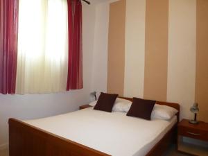 a bedroom with a bed with white sheets and a window at Apartment Mali Iz 16535b in Veli Iž