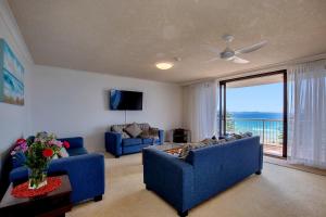 uma sala de estar com dois sofás azuis e uma grande janela em Carool Holiday Apartments em Gold Coast