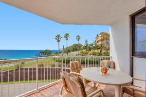 uma varanda com mesa e cadeiras e vista para o oceano em Carool Holiday Apartments em Gold Coast