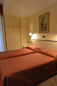 two beds in a hotel room with red sheets at Le Petit Hotel in Turin