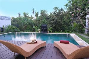 een zwembad met 2 rieten stoelen en een tafel bij Homayoon Private Villa Ubud in Ubud