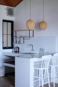a kitchen with a sink and two white chairs at Dip & Doze Boutique Hostel in Canggu