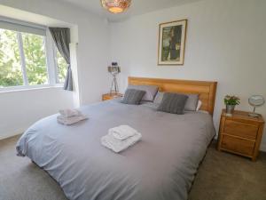 a bedroom with a large bed with two towels on it at Hunter's Cottage in Windermere
