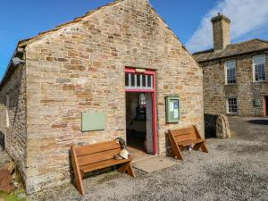 a dog sitting on a bench outside of a building at Field Barn in Alston