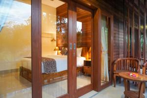 a room with a bed and a glass door at Karang Agartha Lembongan in Nusa Lembongan
