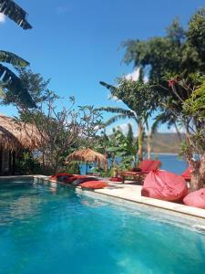 a swimming pool with red cushioned chairs and a resort at Tanjungan in Gili Gede