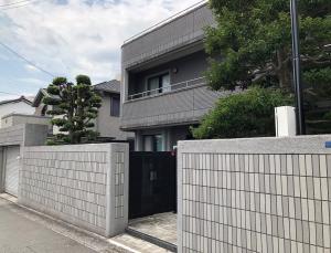 una casa con una puerta negra y una valla en Private Beppu Tanoyu Onsen, en Beppu
