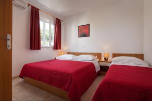two beds in a room with red sheets at Apartments with a parking space Tucepi, Makarska - 14457 in Tučepi
