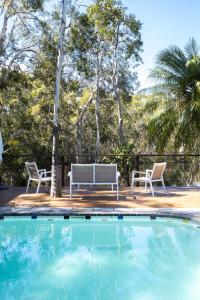 a swimming pool with two chairs and a bench at The Lake House - Cabarita Beach in Cabarita Beach