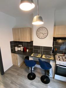 una cocina con 2 sillas azules y un reloj en la pared en Le Petit Gayant, en Douai
