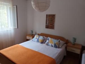 - une chambre avec un lit doté de draps et d'oreillers orange dans l'établissement Apartment Mira - affordable & comfortable, à Supetar