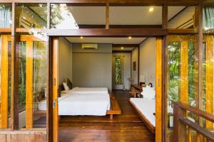 um quarto numa casa na árvore com uma cama e portas de vidro deslizantes em Amaresa Resort & Sky Bar - experience nature em Haad Rin