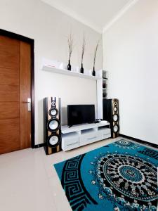 a living room with a television and a rug at Villa petit Tour in Batu