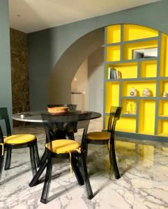 uma sala de jantar com uma mesa preta e cadeiras amarelas em Modern city center apartment em Benevento