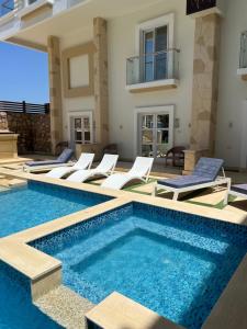 uma villa com uma piscina e espreguiçadeiras em Boka Bay One em Hurghada