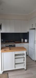 a kitchen with white cabinets and a white refrigerator at Sorrento Bluewater Apartment in Perth +9 photos