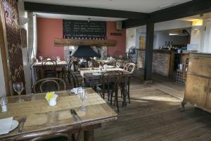 un restaurant avec des tables et des chaises en bois ainsi qu'un tableau noir dans l'établissement The Inn at Emmington, à Chinnor