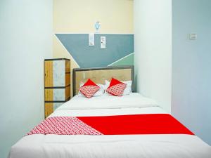 a bed with red and white pillows on it at OYO 91559 Kost Bangau Syariah in Perabumulih