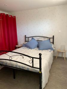 1 dormitorio con cama con almohadas azules y cortina roja en home détente, en Marmande