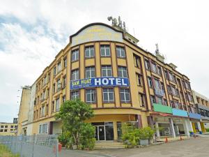 un grande edificio giallo con un cartello sopra di Super OYO 90494 Sam Huat Hotel a Kampong Atap
