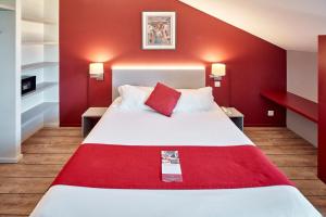 サン・ジャン・ド・リュズにあるHotel Donibane Saint-Jean-de-Luzの赤い壁のベッドが備わるホテルルームです。