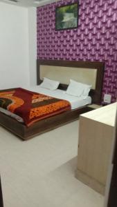 a bedroom with a bed and a purple wall at Hotel Vanya Palace By WB Inn in Agra