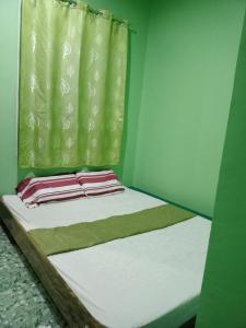 BARRIL GREEN HOMESTAY في Batuan: سرير في غرفة ذات ستارة خضراء