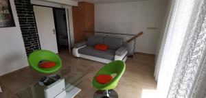sala de estar con sillas verdes y sofá en Tulipán Vendégház, en Balatonberény