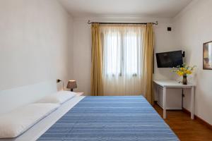 een slaapkamer met een groot bed en een televisie bij Arbatax Sa Omu Bianca in Tortolì
