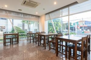 a restaurant with tables and chairs and large windows at 24@Home Hotel in Nonthaburi