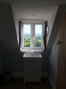 ein Bad mit einem Waschbecken und einem Fenster in der Unterkunft Barn Flat overlooking beautiful Dorset vale in Sherborne