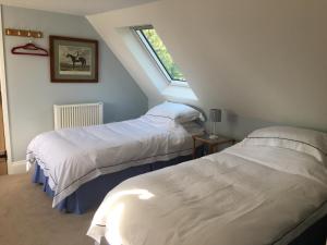 two beds in a attic room with a window at Barn Flat overlooking beautiful Dorset vale in Sherborne