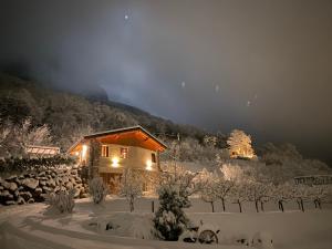 una cabaña en la nieve por la noche con una montaña en Agriturismo Casarai en Zone
