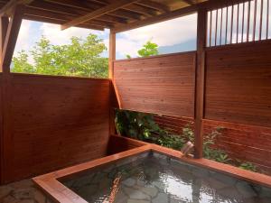 uma banheira de hidromassagem num quintal com uma cerca de madeira em Yufuin Sunday em Yufu