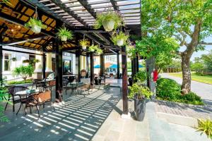 un patio con mesas, sillas y macetas en Le Pavillon Hoi An Luxury Resort & Spa en Hoi An