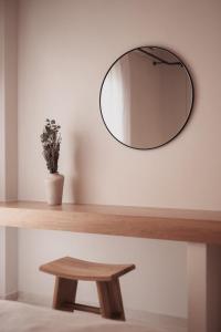 uno specchio rotondo su una parete con tavolo in legno di Om Living Afitos ad Áfitos