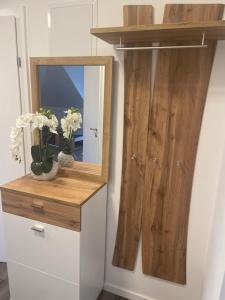 a mirror on a wall next to a cabinet with flowers at Sorinas Home - Comfortable Apartment near Graz - Free Parking in Wagersbach +13 photos