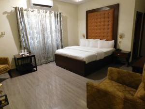 a hotel room with a large bed and a couch at Hotel SR Lounge Multan in Multan