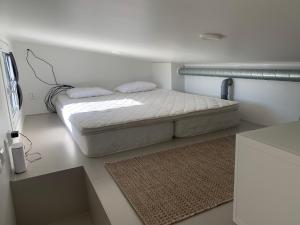 a white bedroom with a bed and a rug at Luxus Tiny House Saagala in Tornio