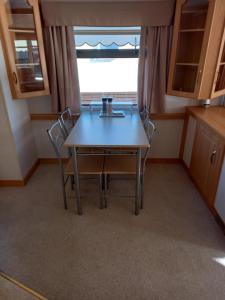 einen Tisch und Stühle in einem Zimmer mit Fenster in der Unterkunft Holiday Home in Forfar