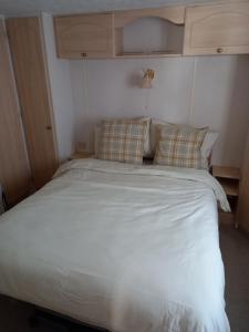 Bett mit weißer Bettwäsche und Kissen in einem Zimmer in der Unterkunft Holiday Home in Forfar