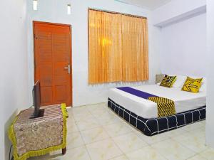 ジャンビにあるSPOT ON 91222 Kanjeng Mami Homestay Syariahのベッドルーム(ベッド1台、テレビ、窓付)
