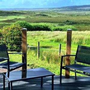 two chairs and a table on a deck with a field at deer green place in Kinloch