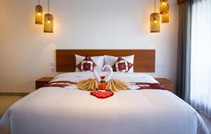 a bedroom with a white bed with a flower arrangement on it at The Kd Suites & Coffee Shop in Munggu