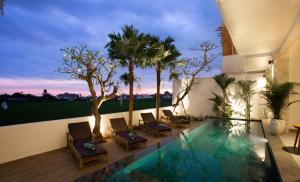 a villa with a swimming pool and palm trees at The Kd Suites & Coffee Shop in Munggu