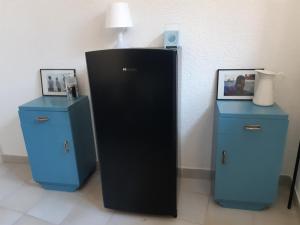 un frigorifero nero seduto accanto a due armadi blu di Mountain Lodge a Raveo