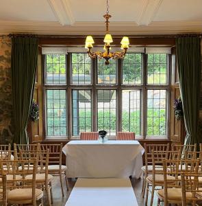 a dining room with a table and chairs and windows at Wildhive Callow Hall in Ashbourne