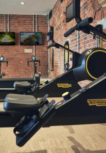 a gym with a treadmill and a brick wall at Wildhive Callow Hall in Ashbourne