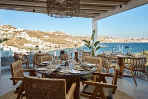 a dining room with a table and chairs and the ocean at Mykonos Princess Hotel in Agios Stefanos